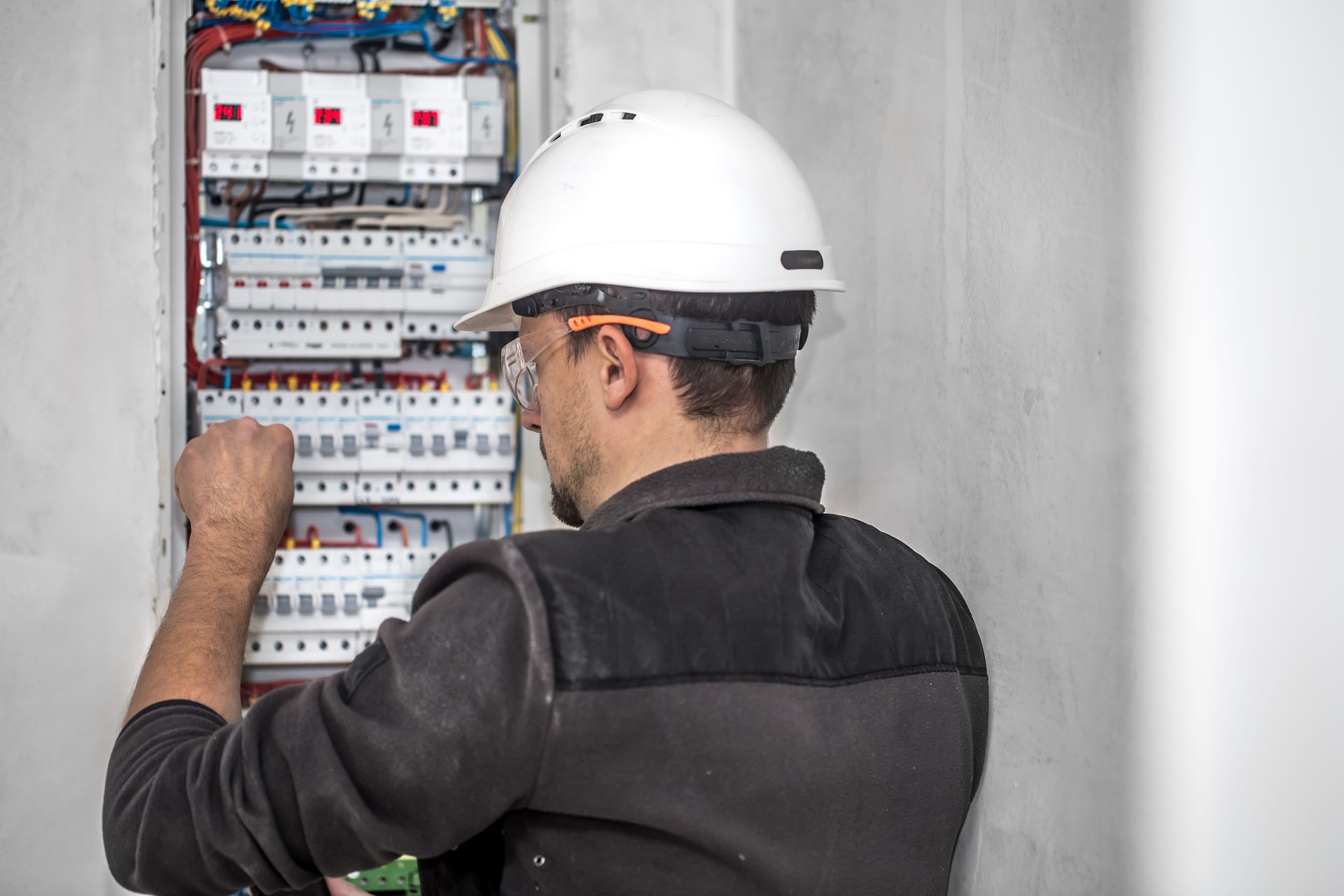 Un técnico eléctrico trabajando en una centralita con fusibles. Instalación y conexión de equipos eléctricos.