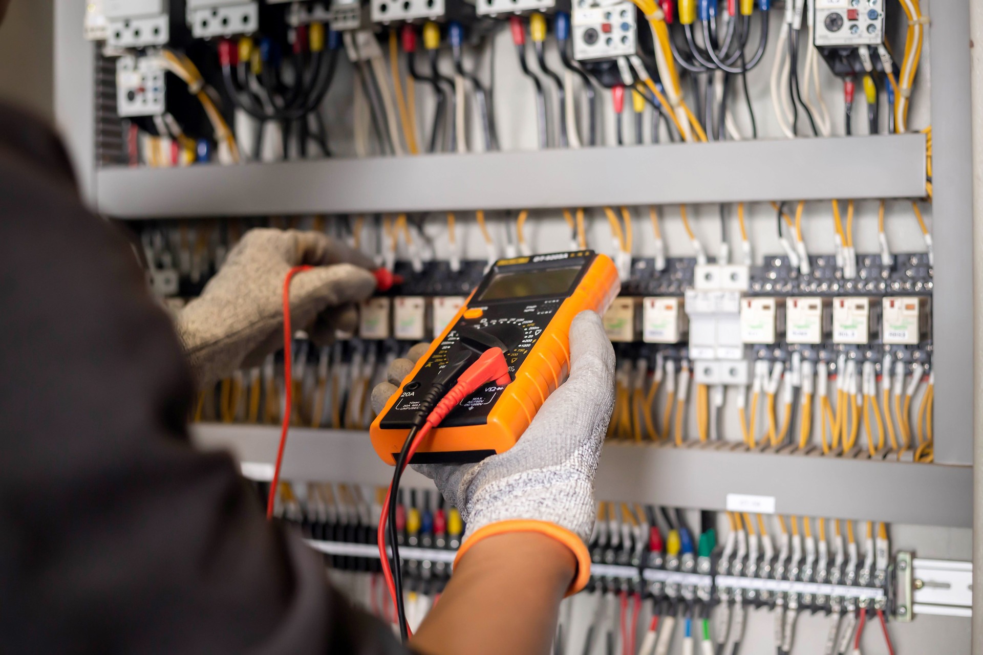 El ingeniero electricista utiliza un multímetro para probar la instalación eléctrica y la corriente de la línea de alimentación en un armario de control del sistema eléctrico.